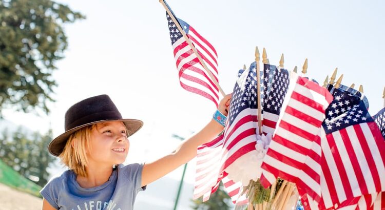 Photo of child reaching for a US flag for post about Independence Day 2023 - Toward a more perfect union